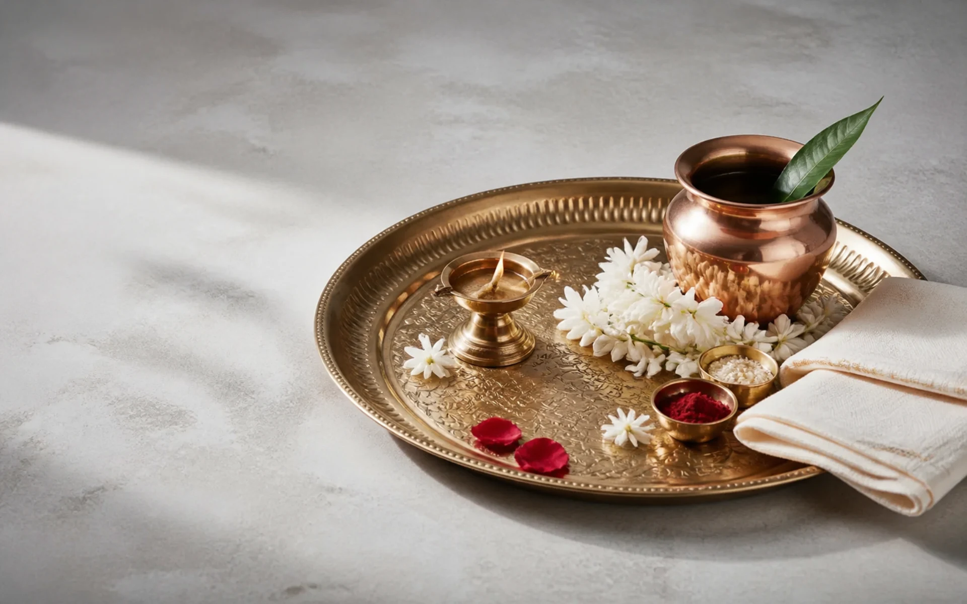 A brass pooja thali prepared with flowers and kumkum